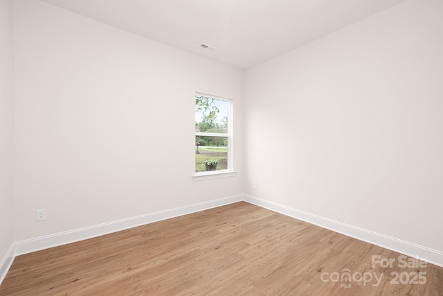 empty room with visible vents, light wood-style flooring, and baseboards