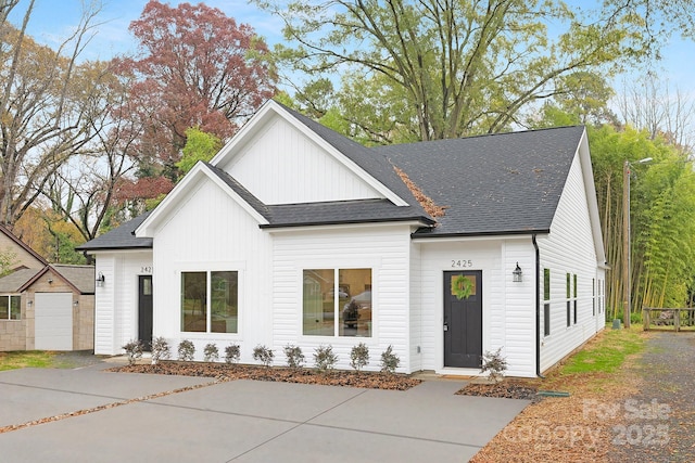 modern inspired farmhouse with board and batten siding, roof with shingles, and an outdoor structure