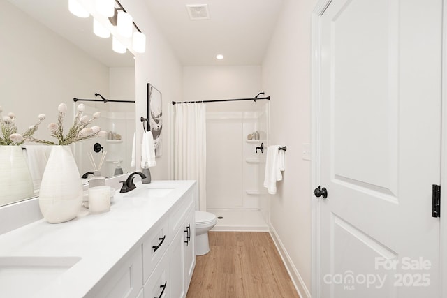 full bath with curtained shower, visible vents, toilet, a sink, and wood finished floors