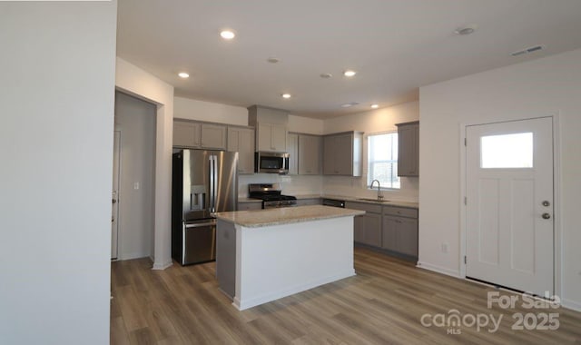 kitchen featuring visible vents, gray cabinets, wood finished floors, stainless steel appliances, and a sink