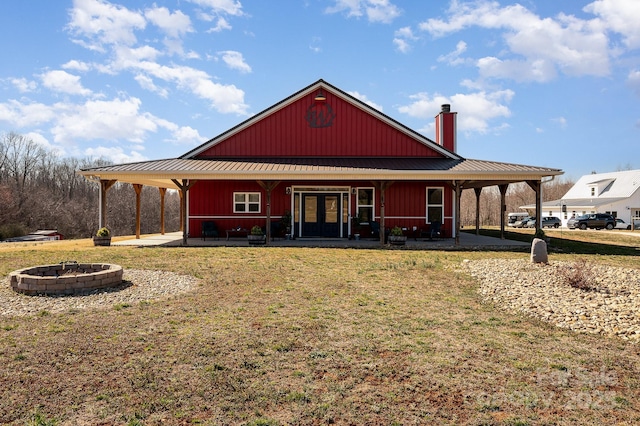 back of house featuring a yard, an outdoor fire pit, french doors, and metal roof