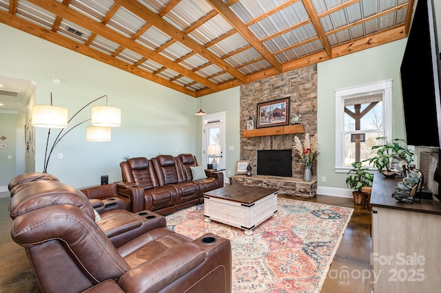 living room with high vaulted ceiling, baseboards, and a stone fireplace