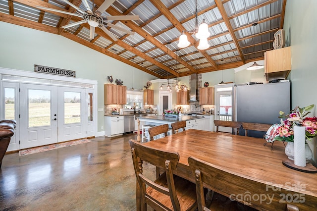 dining space featuring baseboards, ceiling fan, concrete flooring, french doors, and high vaulted ceiling