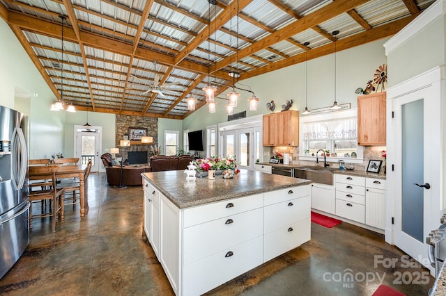 kitchen with open floor plan, stainless steel fridge, a kitchen island, and white cabinetry