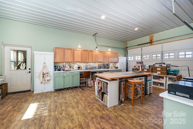 kitchen with dark wood-type flooring, a center island, light countertops, and a kitchen bar