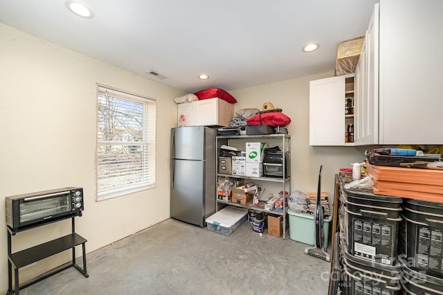 kitchen with freestanding refrigerator, concrete floors, visible vents, and white cabinets