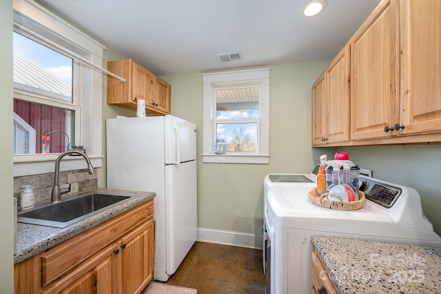 clothes washing area with visible vents, a sink, washer and clothes dryer, and baseboards