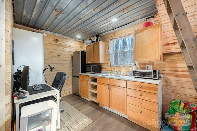 kitchen with light brown cabinets, wooden walls, light countertops, and a sink