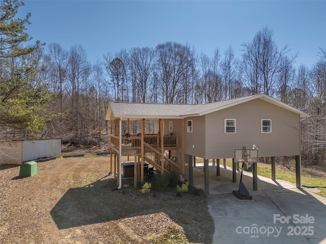 view of front of house with a carport, a shingled roof, stairway, and driveway