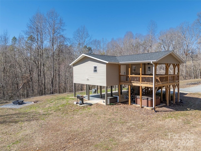 back of house with a patio area, a hot tub, and a shingled roof