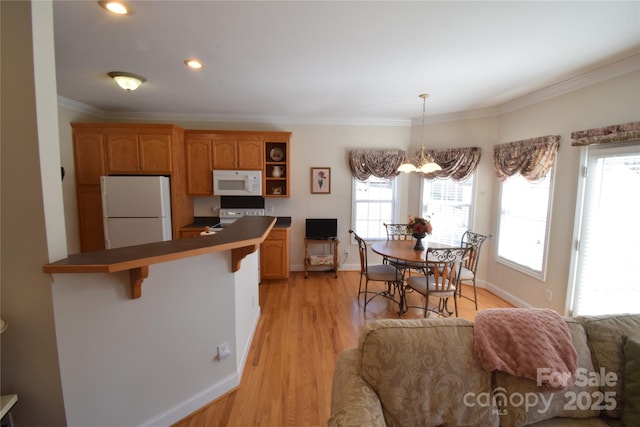 kitchen featuring white appliances, a kitchen breakfast bar, light wood finished floors, dark countertops, and crown molding