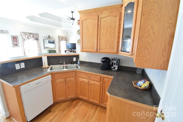 kitchen featuring dark countertops, glass insert cabinets, a peninsula, white dishwasher, and a sink