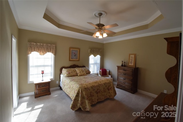 carpeted bedroom featuring crown molding, a tray ceiling, and baseboards