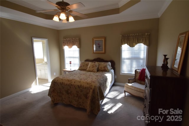 bedroom with connected bathroom, light colored carpet, baseboards, ornamental molding, and a raised ceiling