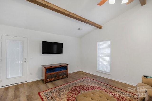 living area featuring a ceiling fan, vaulted ceiling with beams, baseboards, and wood finished floors