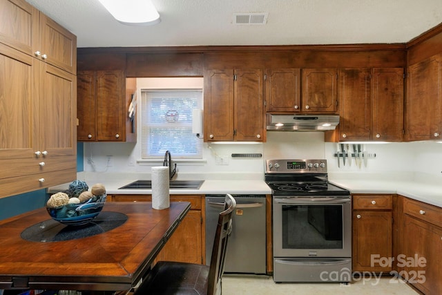 kitchen with light countertops, appliances with stainless steel finishes, visible vents, and under cabinet range hood