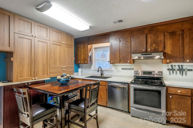 kitchen with stainless steel appliances, a sink, light countertops, and under cabinet range hood