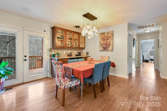 dining space featuring french doors, light wood finished floors, visible vents, and baseboards