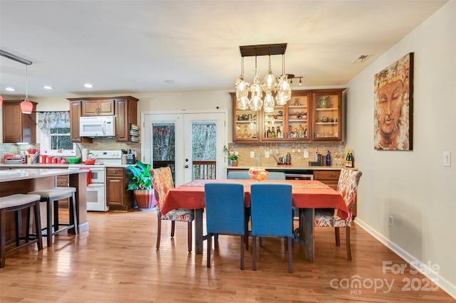 dining room featuring light wood finished floors, french doors, visible vents, and baseboards