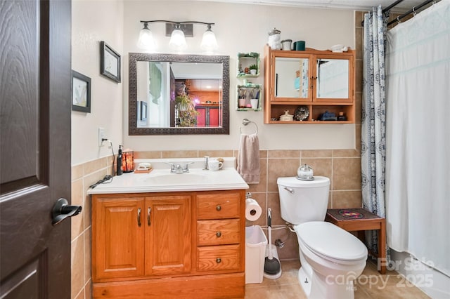 bathroom featuring tile patterned flooring, tile walls, toilet, and vanity