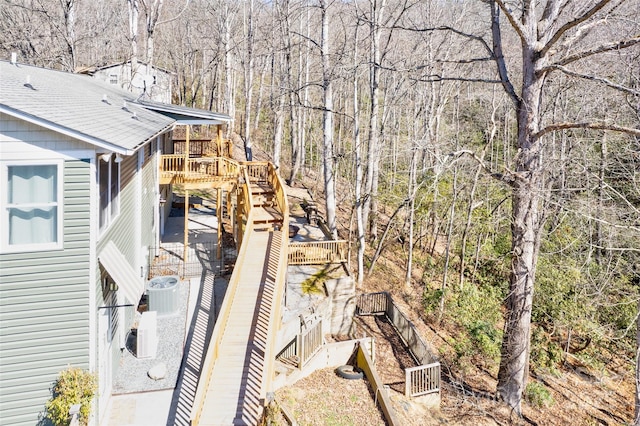 view of side of home with a deck, fence, and central air condition unit