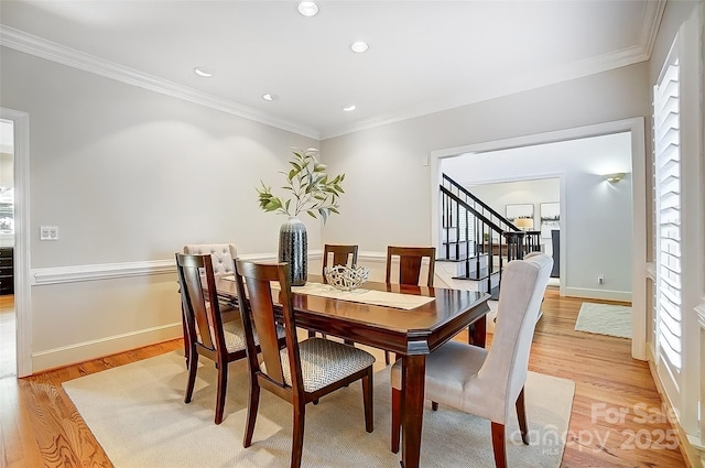 dining space with ornamental molding, light wood finished floors, and stairs