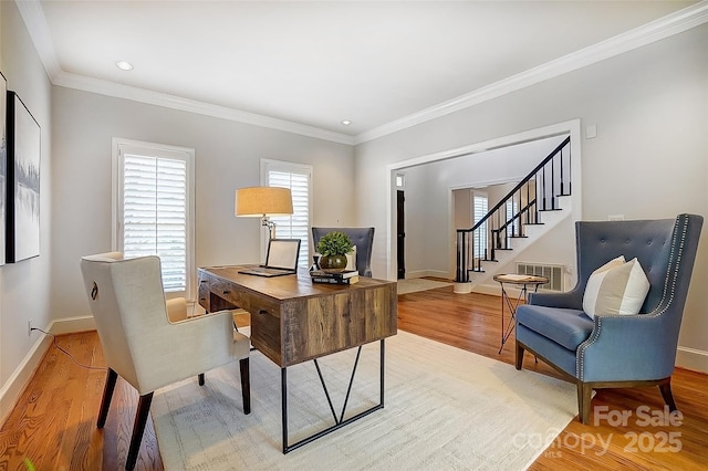 office space featuring crown molding, light wood-type flooring, visible vents, and baseboards