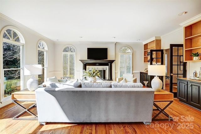 living room with light wood finished floors, a fireplace, and ornamental molding