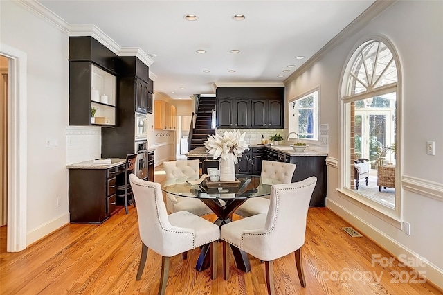 dining space featuring stairway, light wood-style flooring, visible vents, and crown molding