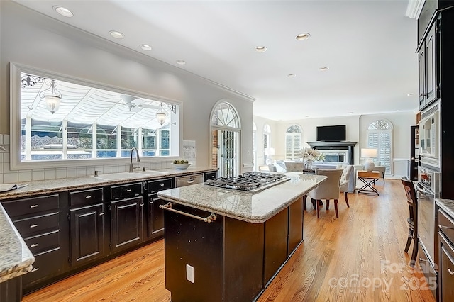 kitchen with a center island, stainless steel gas cooktop, a healthy amount of sunlight, and a sink