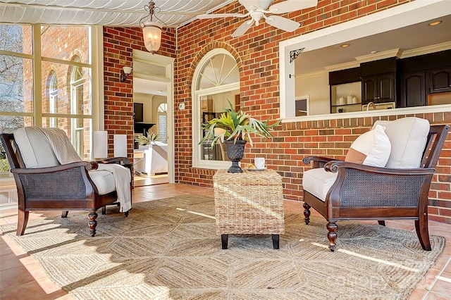 interior space featuring ornamental molding, ceiling fan, brick wall, and tile patterned floors