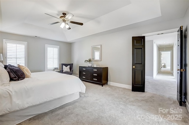 bedroom with attic access, baseboards, light colored carpet, ceiling fan, and a tray ceiling