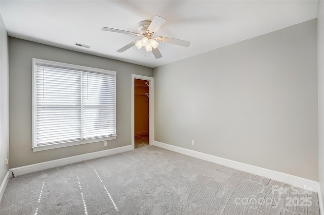 spare room with carpet flooring, ceiling fan, visible vents, and baseboards