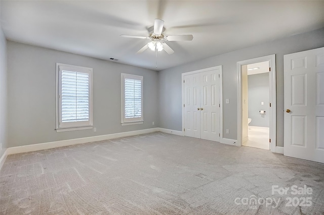 unfurnished bedroom featuring baseboards, visible vents, connected bathroom, light colored carpet, and a closet