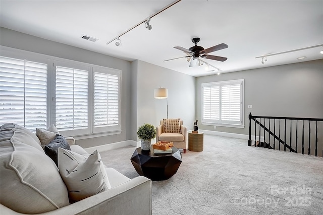 carpeted living room with rail lighting, baseboards, visible vents, and a ceiling fan