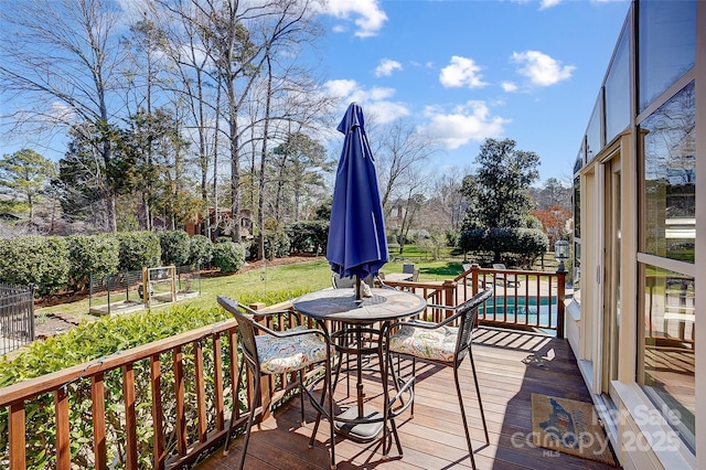 wooden terrace featuring an outdoor pool and a lawn