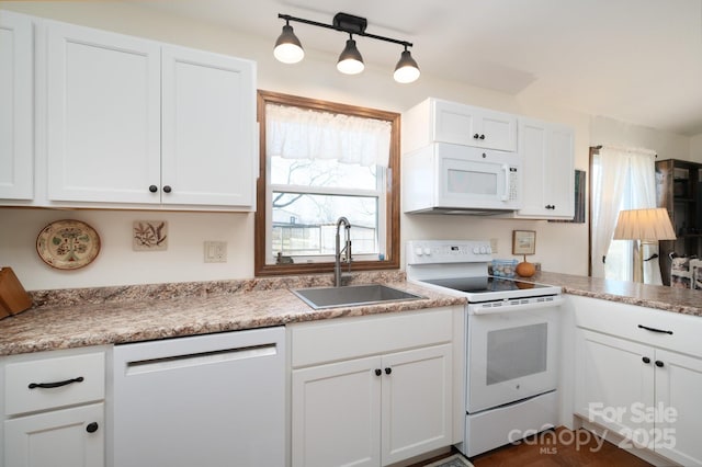 kitchen with white appliances, white cabinetry, light countertops, and a sink