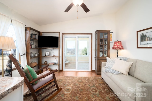 living area with a wealth of natural light, vaulted ceiling, and wood finished floors