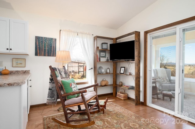 sitting room with lofted ceiling, baseboards, and light wood finished floors