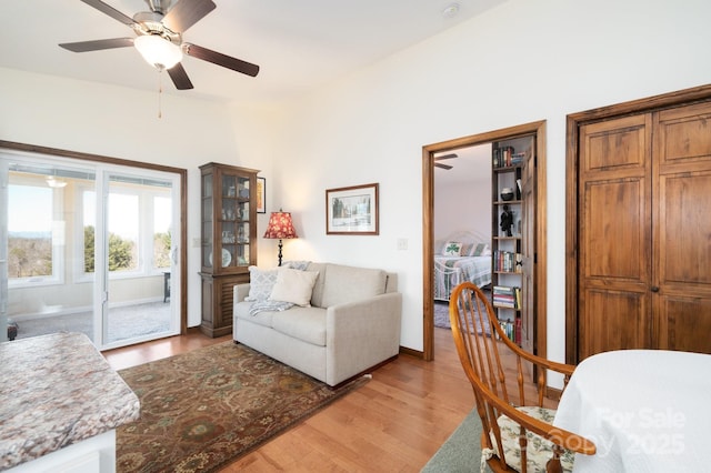 living room featuring a ceiling fan, light wood-style flooring, and baseboards