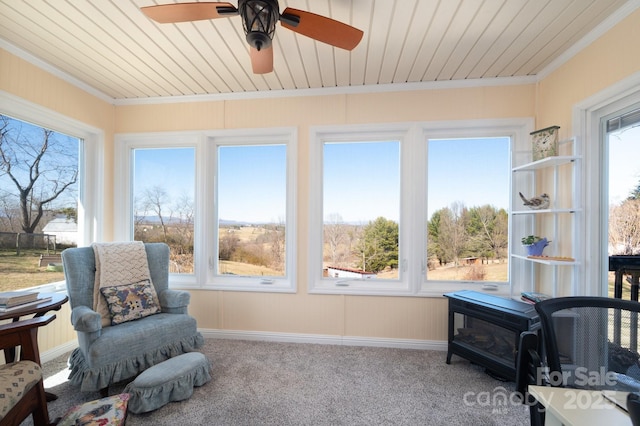 sunroom featuring wood ceiling, a wood stove, and ceiling fan