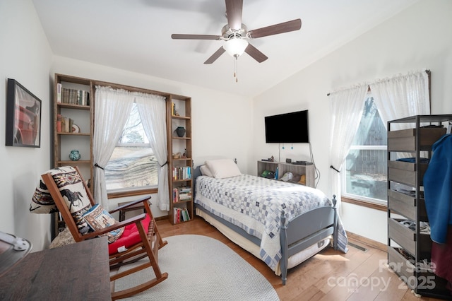 bedroom with a ceiling fan, lofted ceiling, and wood finished floors