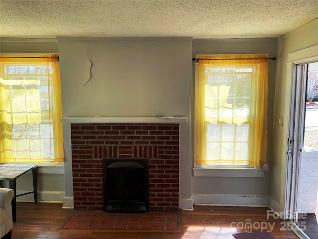 living room featuring a brick fireplace, plenty of natural light, dark wood finished floors, and a textured ceiling