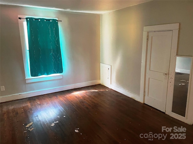 empty room with dark wood-style flooring and baseboards