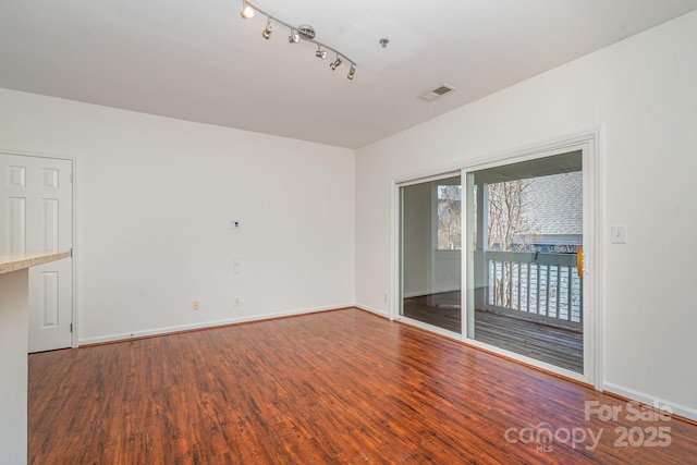 spare room featuring visible vents, baseboards, and wood finished floors