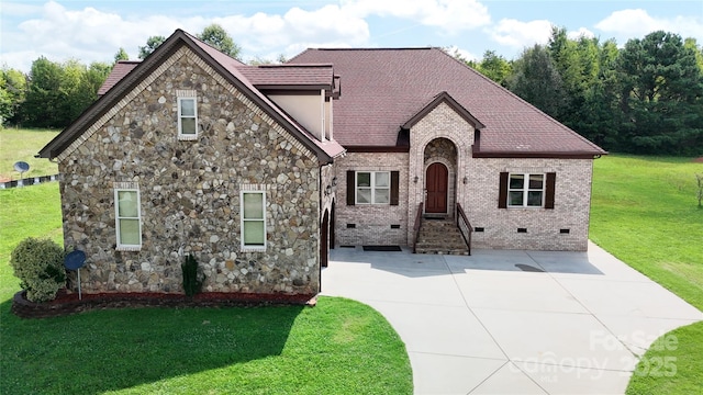 view of front facade with roof with shingles, brick siding, crawl space, and a front yard