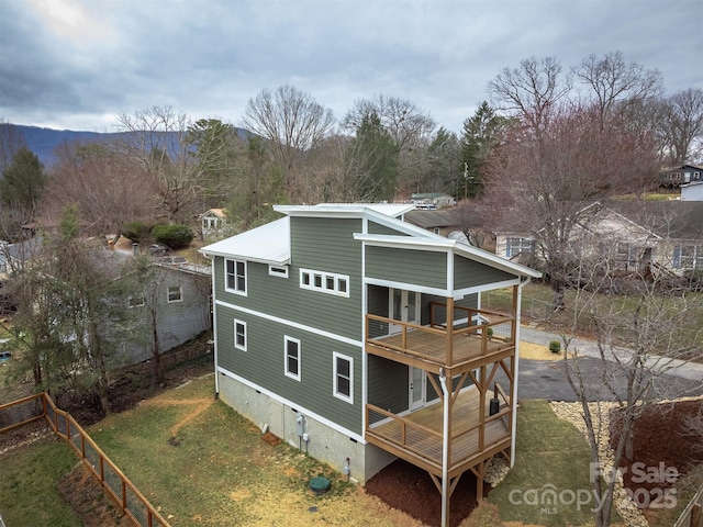 rear view of house with metal roof, a lawn, and a balcony