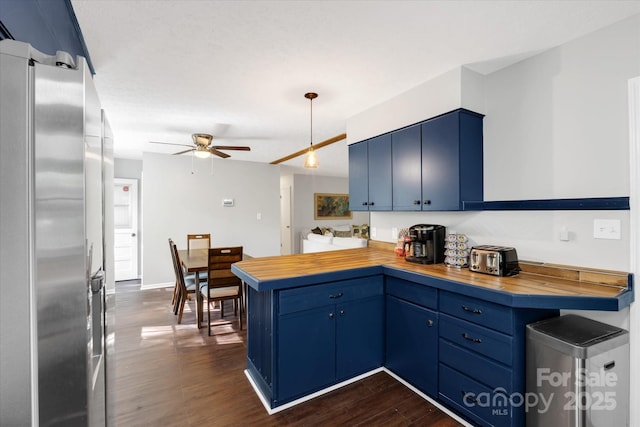 kitchen featuring a peninsula, butcher block counters, blue cabinetry, freestanding refrigerator, and pendant lighting