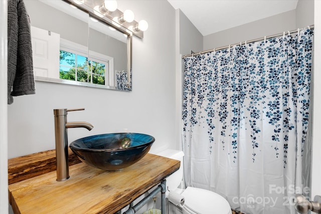 full bathroom with curtained shower, a sink, and toilet