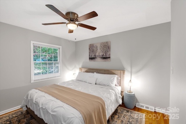 bedroom featuring a ceiling fan, dark wood-style flooring, visible vents, and baseboards